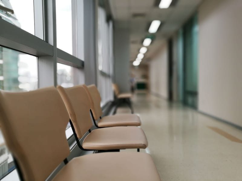 An empty run of waiting-room seating along a clinic corridor