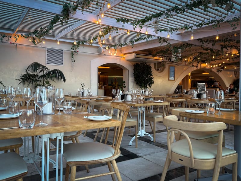 A restaurant dining room laid up before service, tables set under pendant lighting