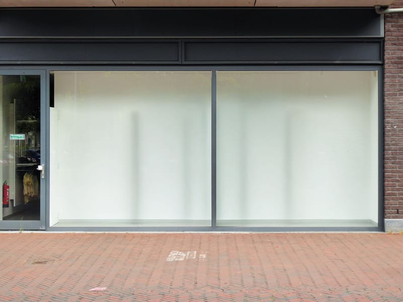 A vacant retail unit with blank display windows and a glazed entrance door