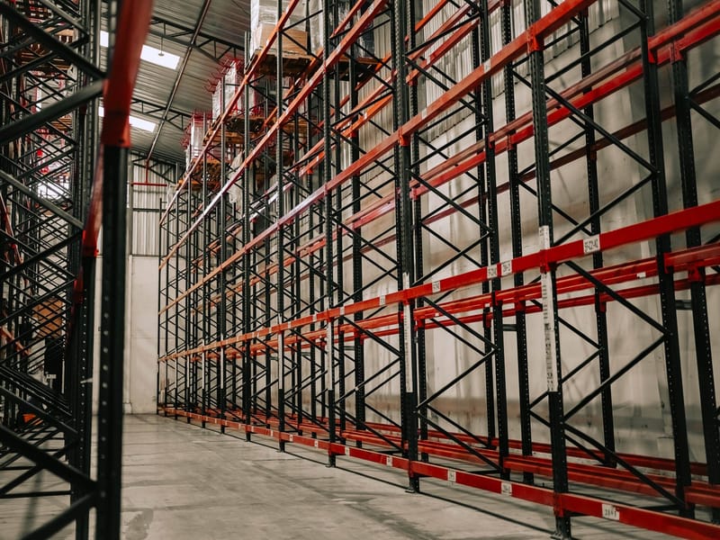 The interior of a warehouse, steel pallet racking running the length of the building