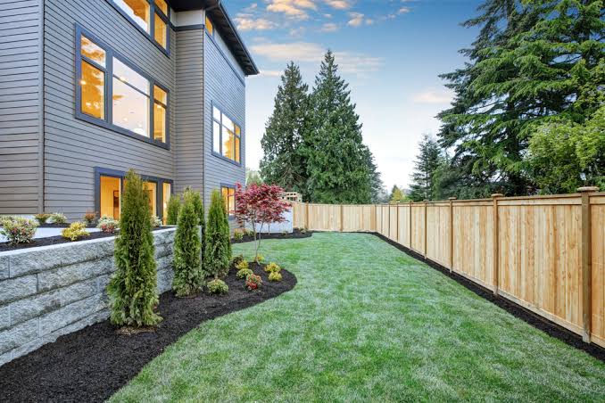 A stained privacy fence running along a back yard