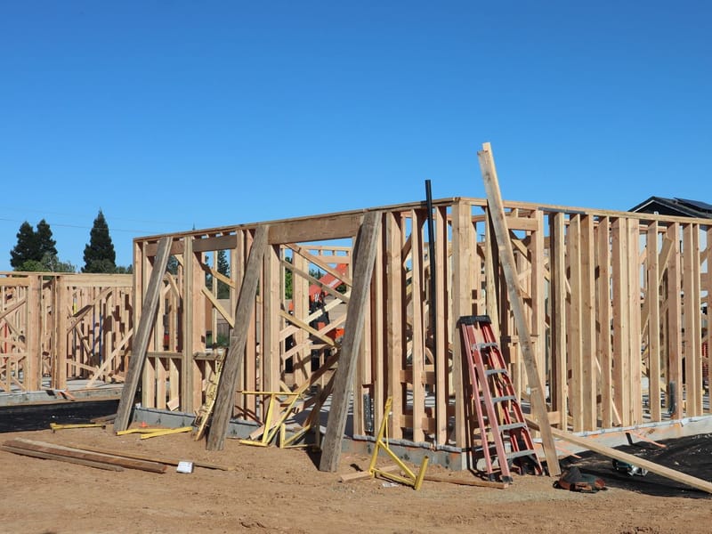 A house under construction, timber wall framing up and braced on a poured slab