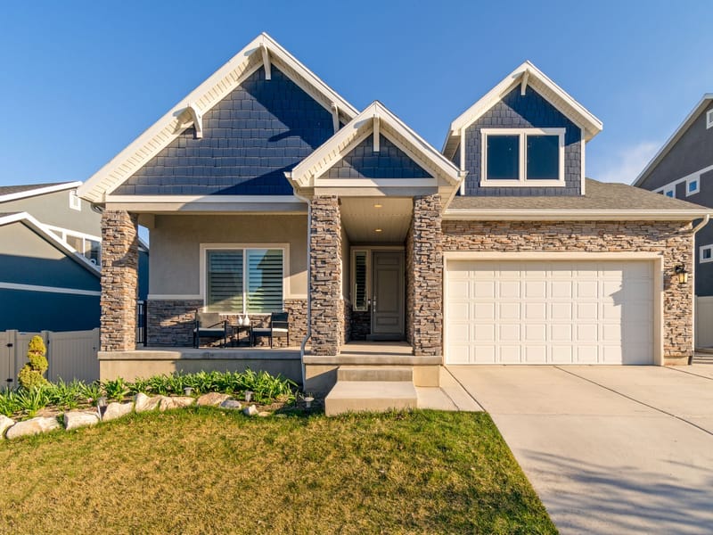 A two-storey suburban house with a stone porch, gabled roof and attached garage