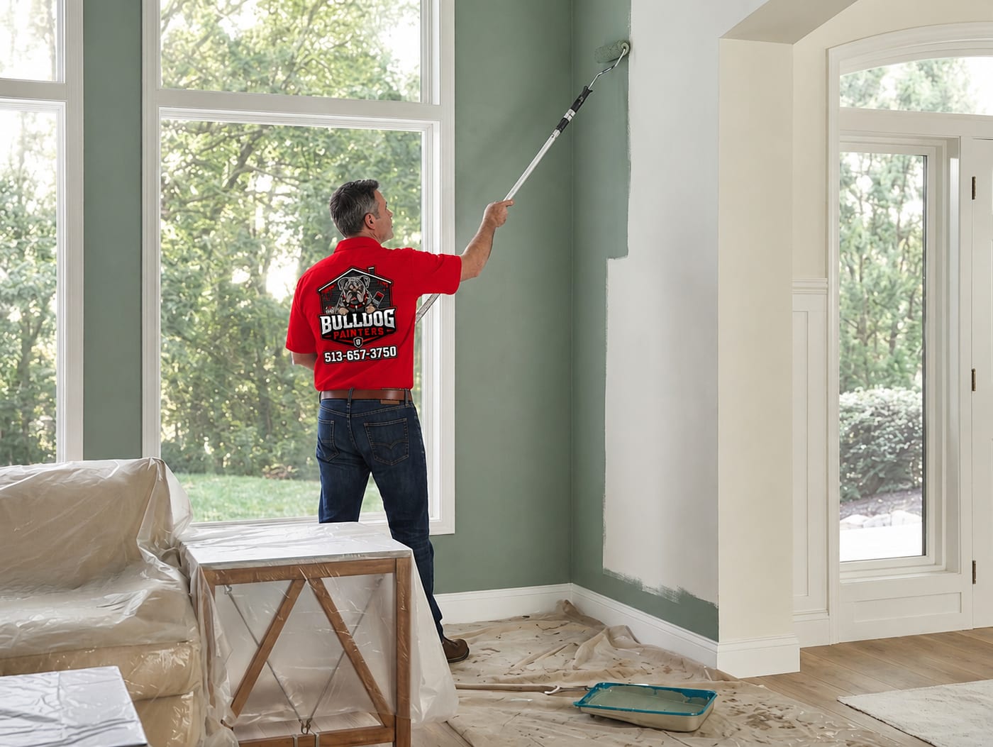 A Bulldog Painters painter rolling a finish coat onto an interior wall, floors covered