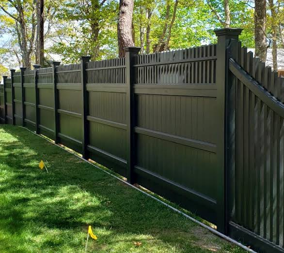 A white vinyl fence along a back yard