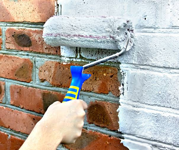 A Bulldog Painters painter rolling a stucco wall, the fresh coat cutting a clean edge against the old